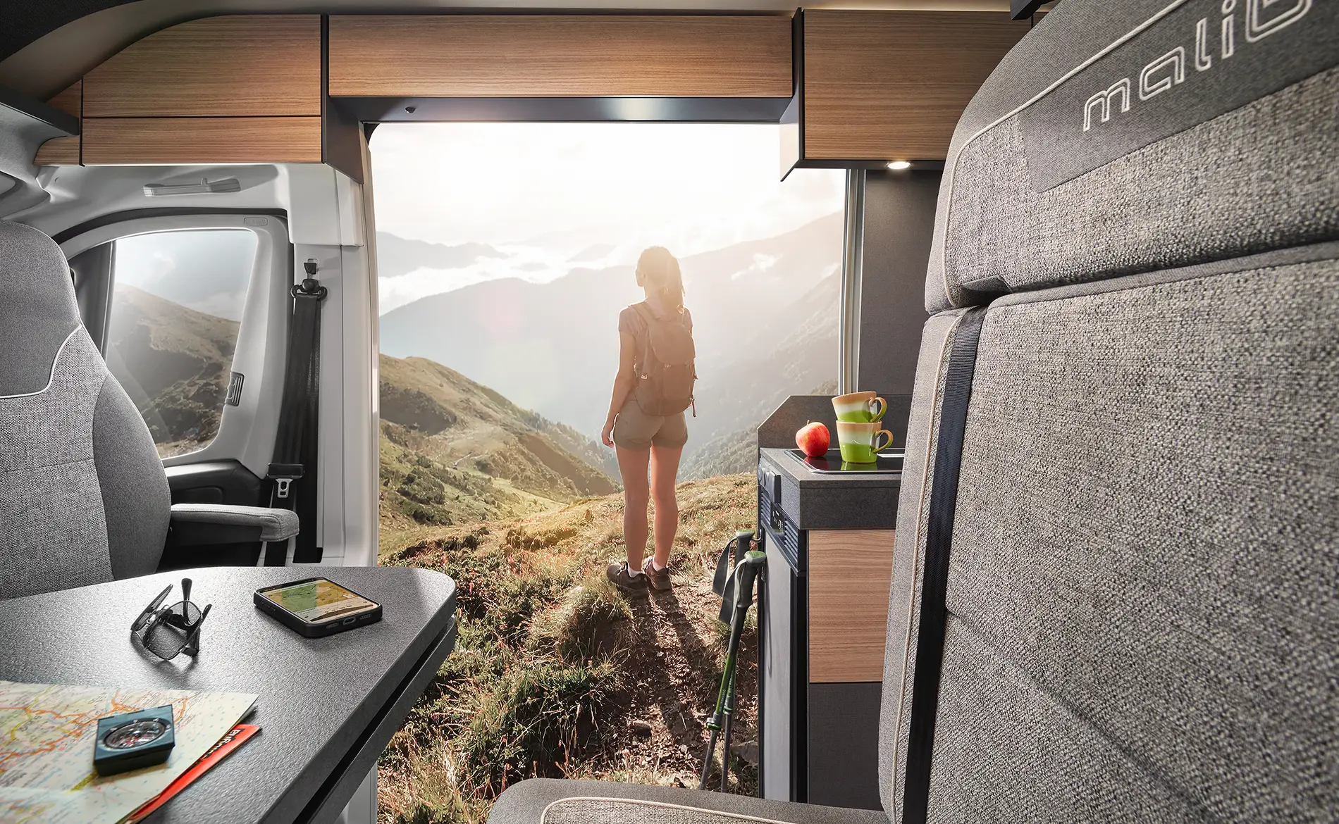 Interieur eines Wohnmobils mit einer Person, die auf eine Berglandschaft schaut.