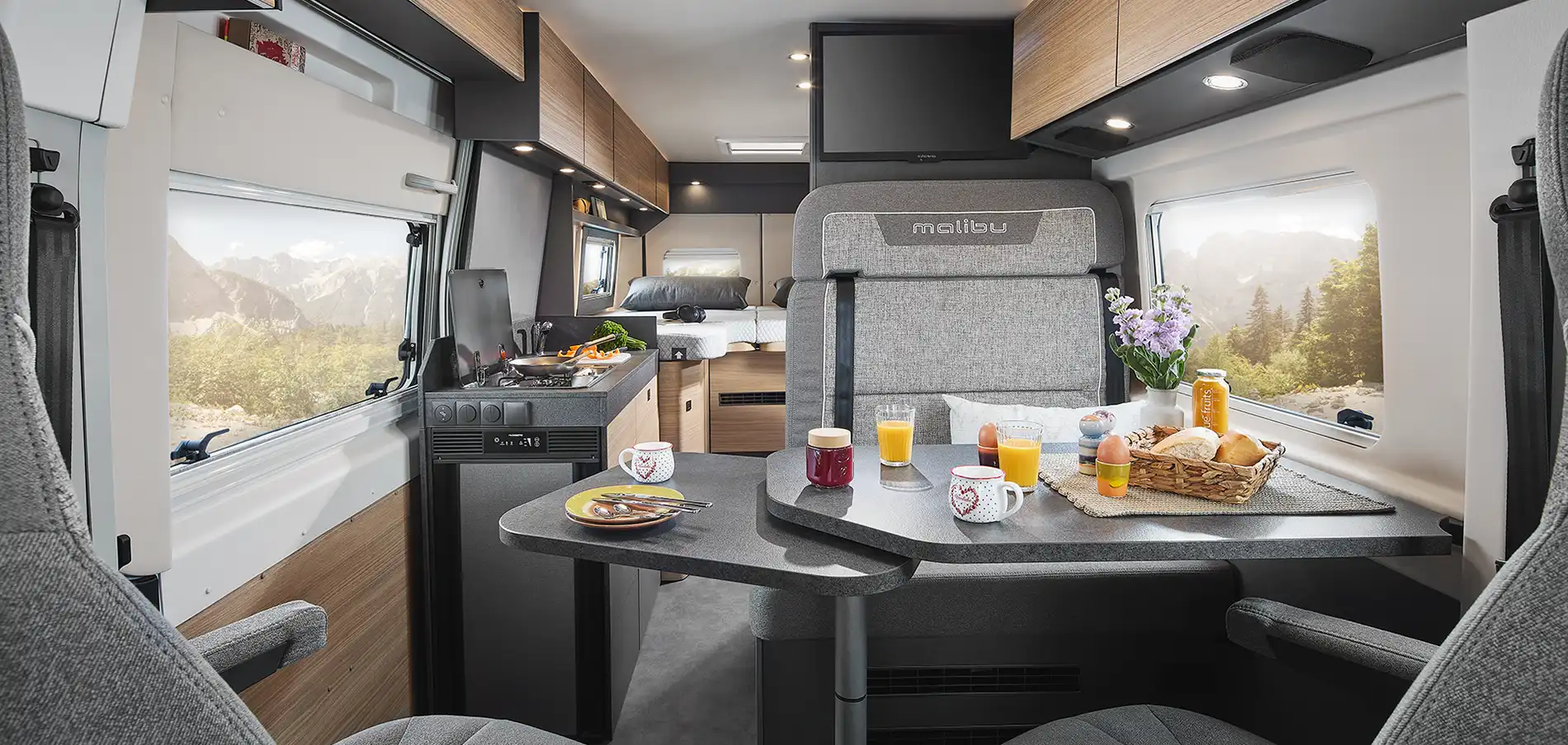 Innenansicht eines Wohnmobils mit einem Tisch, der Frühstück und Getränke zeigt.