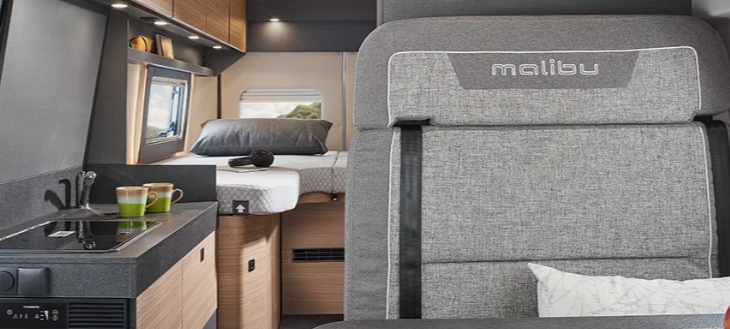 Innenansicht eines Malibu Wohnmobils mit grauen Polstern und Küchenbereich.