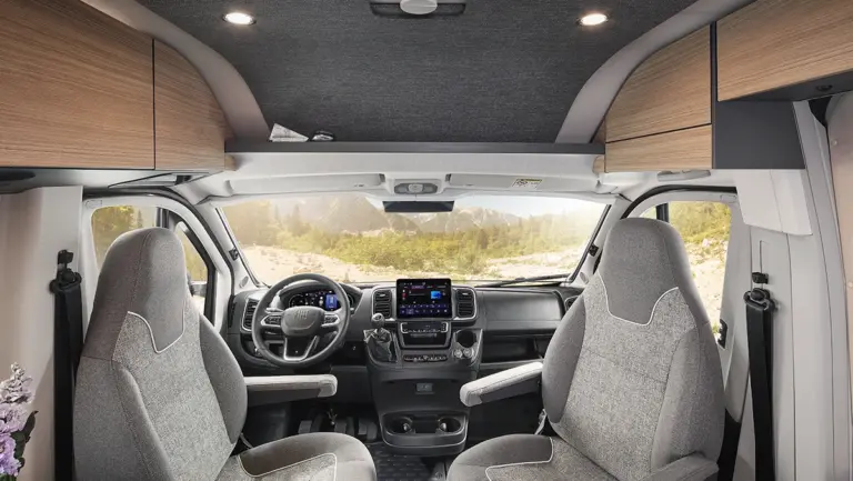 Fahrerhaus eines Wohnmobils mit zwei grauen Sitzen und einem Armaturenbrett in einem modernen Design.
