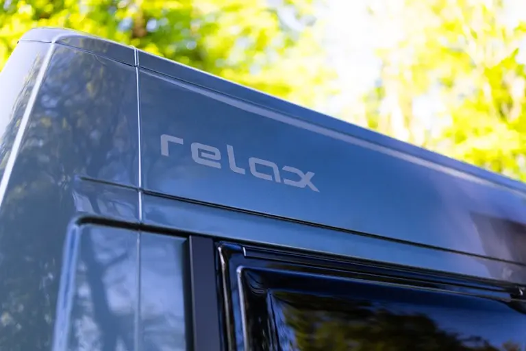 Der Schriftzug 'relax' in einer modernen Schriftart auf einer grauen Oberfläche.