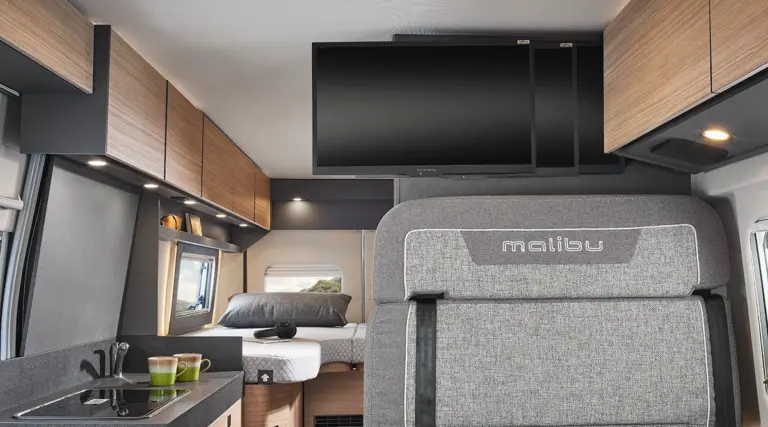 Innenansicht eines Malibu Wohnmobils mit einem Fernseher und Holzschränken.